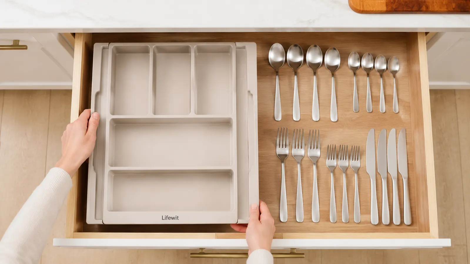 Person pulling a drawer completely out of a kitchen cabinet and setting it on a counter to sort its contents